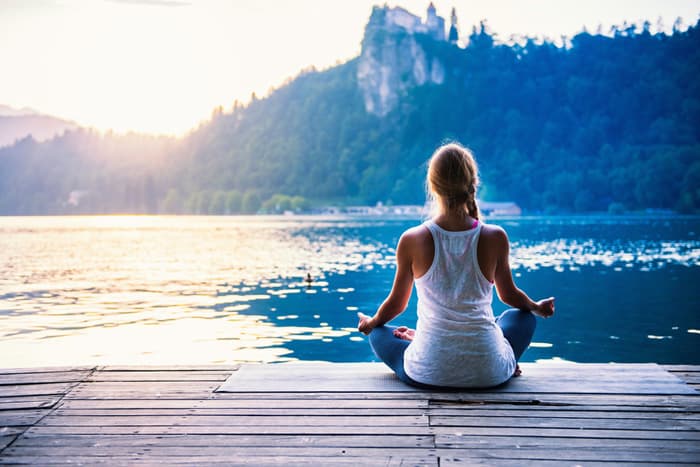 Holistic nursing practitioner meditating on dock