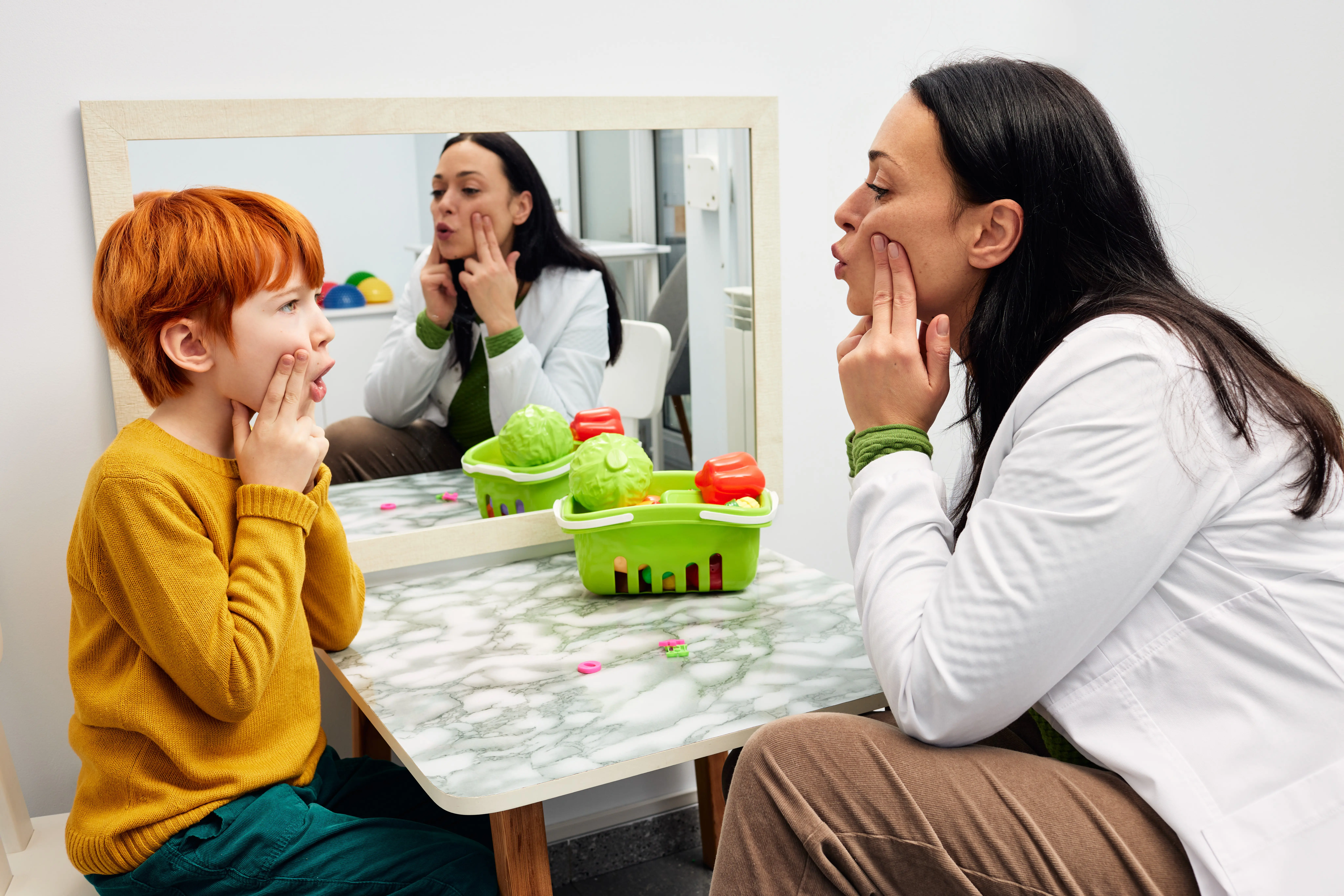 Speech therapist shaping a boy's mouth in order for his to make correct sound